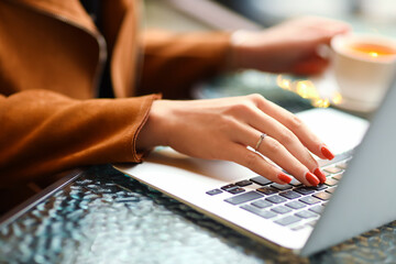 Young woman with beautiful manicure working with laptop, closeup