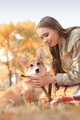 Young woman with cute Corgi dog in autumn park