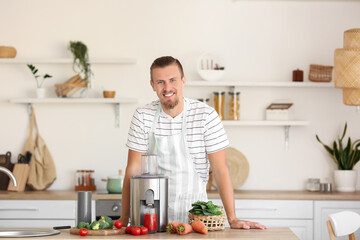 Young man with fresh vegetables and modern juicer in kitchen