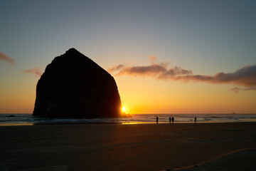 Naklejka na ściany i meble Sunset behind Haystack Rock Cannon Beach. Sunset at Haystack Rock in Cannon Beach, Oregon as the surf washes up onto the beach. United States.