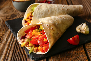 Board of tasty Mexican burritos with vegetables on wooden background, closeup