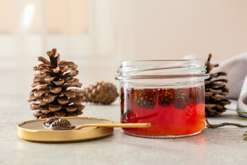 Jar of tasty pine cone jam on light background, closeup