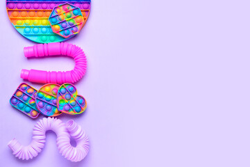 Colorful Pop Tubes and Pop it fidget toys on purple background - obrazy, fototapety, plakaty