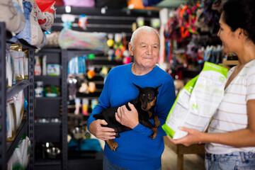 Fototapeta na wymiar Pet store employee helps an elderly man choose dry dog food