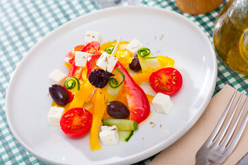 Healthy summer salad with fresh tomatoes, cucumber, bell pepper, feta cheese and olives seasoned with herbs. High quality photo