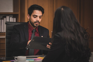 Closeup shot of Millennial Indian Asian professional successful executive bearded male businessman manager entrepreneur in formal suit sitting smiling shaking hands with businesswoman colleague