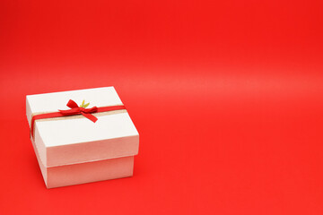 Caja de regalo color blanco sobre un fondo rojo. Espacio para texto al lado derecho.