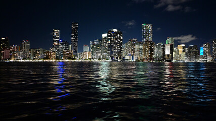 Skyline of brightly lit City of Miami, Florida reflected in Biscayne Bay at night.