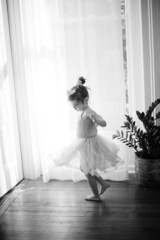 Beautiful toddler ballerina dancing around in living room 