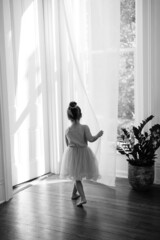 Child dressed as a princess looking out the window of a living room
