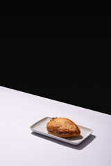 Freshly baked Mexican artisan bread on a white plate on a white table and a black wall in the background
