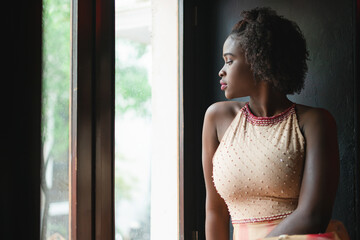 Young Latin black woman in elegant dress with afro hair sitting in front of an edge with natural light