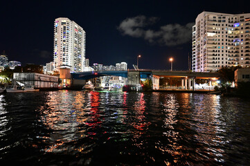 Brightly illuminated office and residential buildings on Miami River in Miami, Florida reflected in water at night.