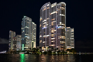Fototapeta na wymiar Brightly illuminated office and residential buildings on Miami River in Miami, Florida reflected in water at night.