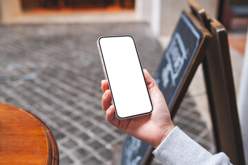 Mockup image of a woman holding and using mobile phone in the outdoors