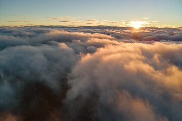 Aerial view from airplane window at high altitude of dense puffy cumulus clouds flying in evening