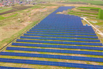 Fototapeta premium Aerial view of big sustainable electric power plant with many rows of solar photovoltaic panels for producing clean ecological electrical energy. Renewable electricity with zero emission concept