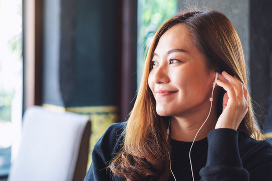Portrait image of a beautiful woman putting on an earphones to listen to music