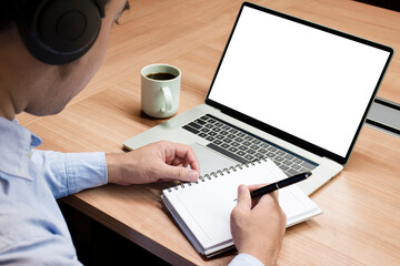 Businessman hand holding a pen to paperwork with white screen background mock up on display laptop...