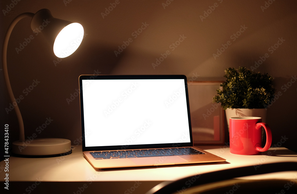 Poster mock up computer laptop with empty display and glowing lamp on wooden table in dark room.