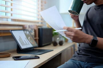 Serious businessman reading business document in home workplace..