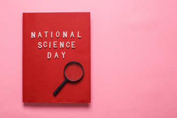 Flat lay of a red book with the inscription national science day isolated on a pink background