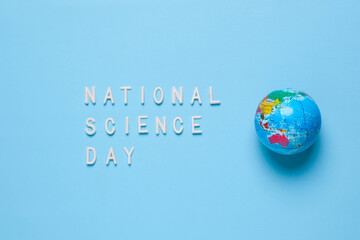 Flat lay of National Science Day inscription with globe isolated on blue background
