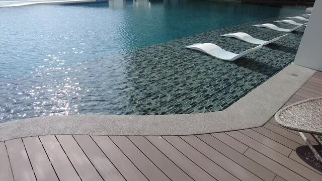 Rest place of chair at swimming pool with blue gentle water