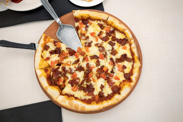Homemade pizza with bacon, ham and cheese on a wooden tray