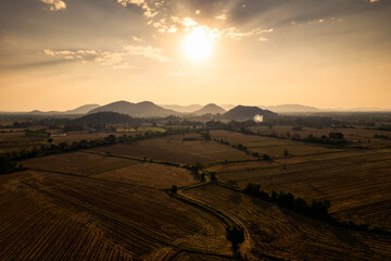 Obraz premium Colorful sunset over mountain and harvested paddy fields in farmland at countryside