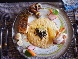 Seafood risotto (Krabi wing shell, prawn, scallop and seabass) serving on the plate. Luxury rice...