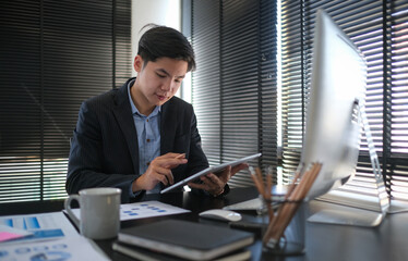 Happy businessman using stylus pen writing some information on digital tablet.