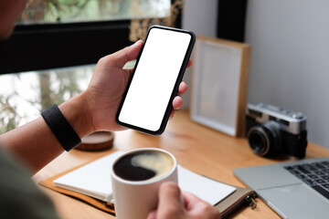 Young man sitting in home office and using smart phone.	
