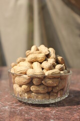Bunch of unpeeled peanuts on a glass bowl