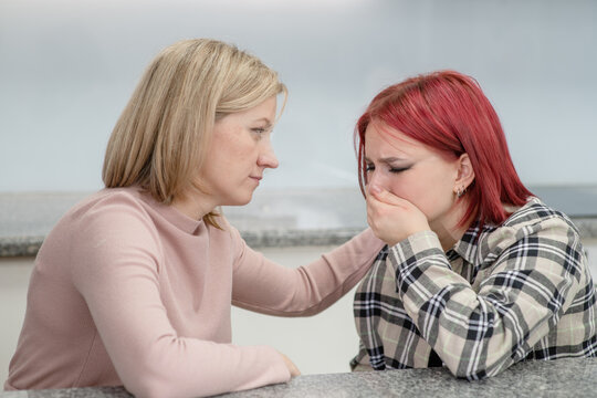 Careful woman and teen girl talk together, worried parent calms crying girl. Teenagers problem concept