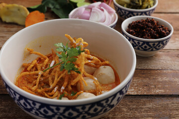 Local northern Thai food Egg noodle curry with meatballs on wood background