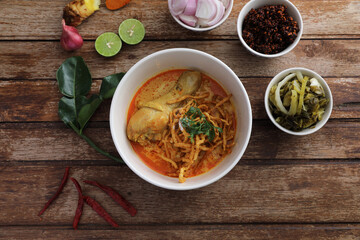 Local northern Thai food Egg noodle curry with chicken on wood background