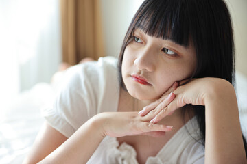 Beautiful young Asian woman sleeping on bed relaxing in the morning light with white room