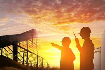 Fototapeta premium Silhouette of executive and engineer working at factory and warehouse building sunset background.