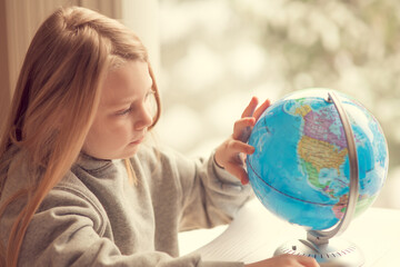 Fototapeta premium Little girl with a globe, child studying, homeschooling 