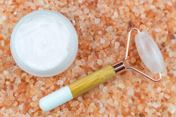 The rose quartz face roller, pink bath salt and face cream. Skin care concept. 