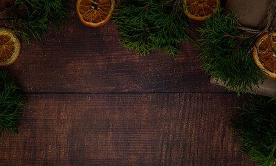 Dark wooden holiday background with sliced dried oranges and fir tree branches on a side with copy space for text