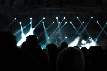 Fototapeta na wymiar Concert background. Stage with spotlights and silhouette of people.