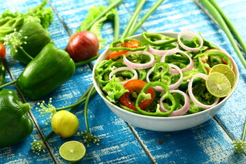 Bowl of delicious capsicum salad with onions, tomatoes and lime slice..