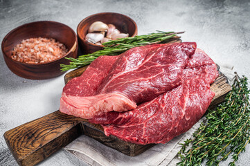 Fresh raw beef meat sirloin steaks, herbs and spices around cutting board. White background. Top view