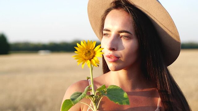 Young brunette with sunflower in field