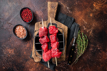 Lamb shish kebab, Raw meat Skewers with herbs on grill. Dark background. Top view