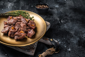 Chopped Grilled Diced Beef garlic steak on a plate with thyme. Black background. Top view. Copy...