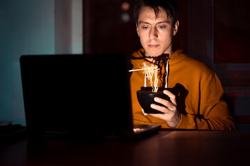 Man is eating noodles and watching movies.