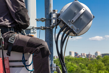 Professional industrial climber in uniform and climber equipment on the telecommunication tower is...